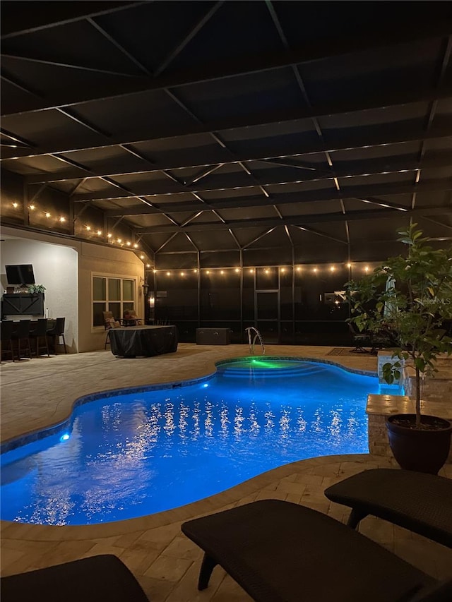 pool at twilight with a patio, a lanai, and an outdoor pool