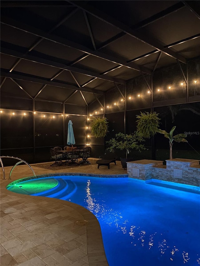 pool at twilight featuring a lanai, a patio area, and an outdoor pool