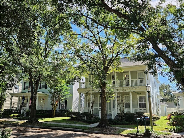 view of front of house featuring a balcony and a front lawn