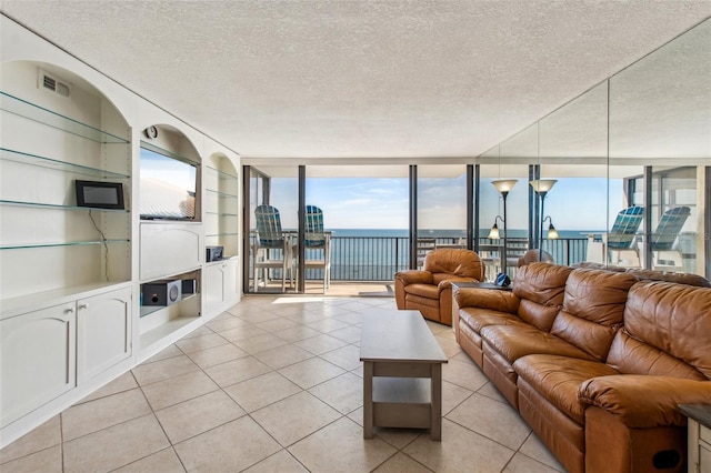 unfurnished living room with light tile patterned floors, a textured ceiling, built in features, and a wall of windows