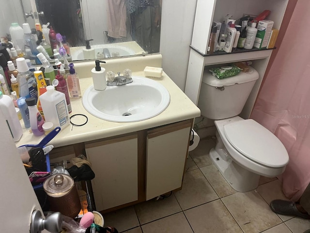 bathroom with toilet, vanity, and tile patterned flooring