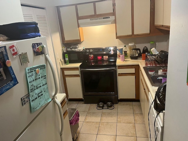 kitchen featuring white fridge, light tile patterned flooring, electric stove, and sink