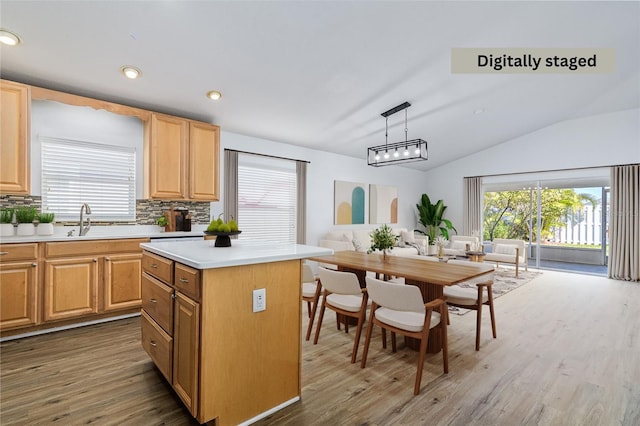 kitchen with dark wood-type flooring, hanging light fixtures, tasteful backsplash, a kitchen island, and vaulted ceiling