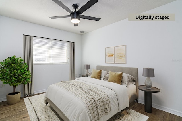 bedroom featuring ceiling fan, wood-type flooring, and a textured ceiling