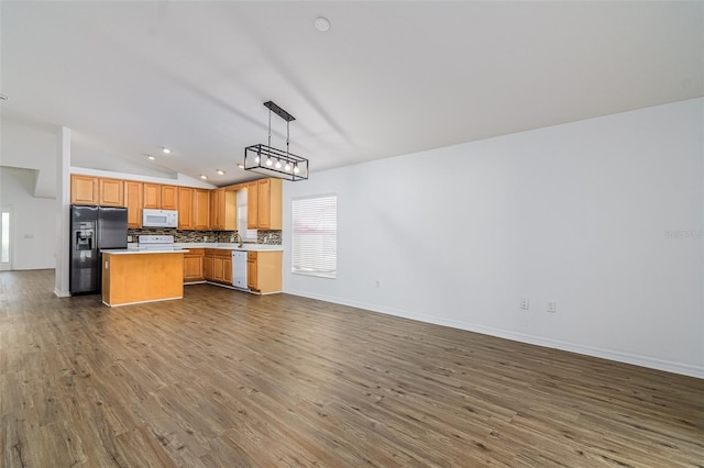 kitchen with pendant lighting, white appliances, a center island, tasteful backsplash, and vaulted ceiling