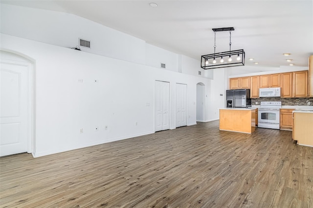 kitchen featuring pendant lighting, wood-type flooring, backsplash, a center island, and white appliances