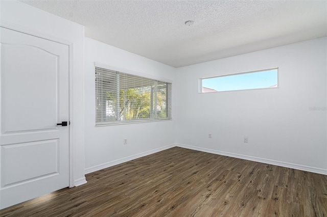 unfurnished room with dark hardwood / wood-style flooring and a textured ceiling