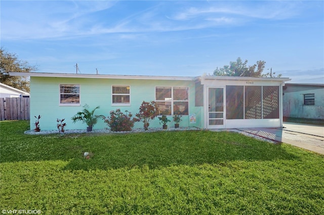 rear view of house featuring a lawn and a sunroom