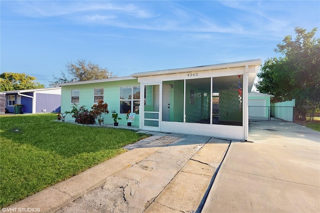 view of front of house featuring a sunroom, a garage, an outdoor structure, and a front yard