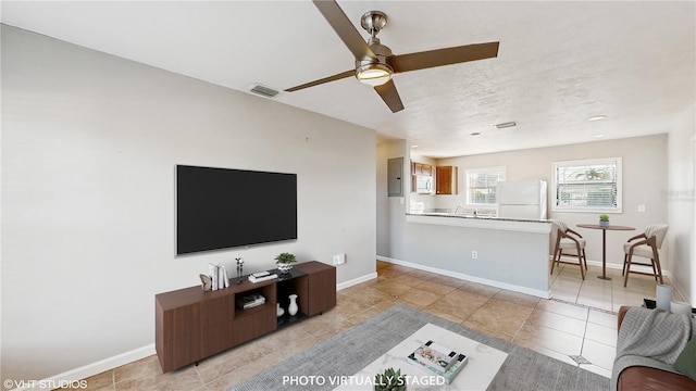 living room with light tile patterned floors, electric panel, and ceiling fan