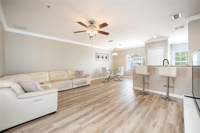 living room with light wood-type flooring, ceiling fan, and ornamental molding