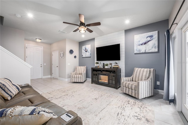 tiled living room featuring ceiling fan and a fireplace