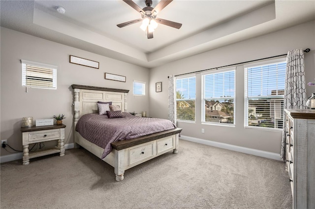 carpeted bedroom with a tray ceiling and ceiling fan