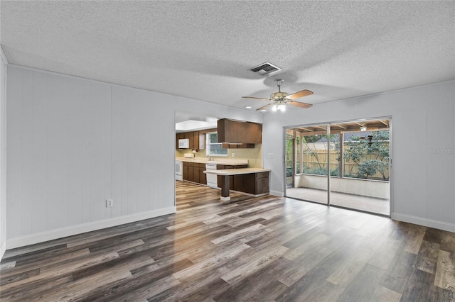 unfurnished living room with a textured ceiling, ceiling fan, and dark wood-type flooring