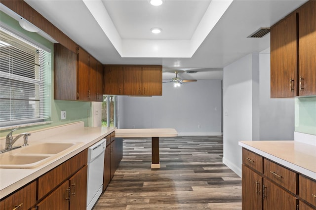 kitchen featuring ceiling fan, sink, a raised ceiling, dark hardwood / wood-style flooring, and white dishwasher