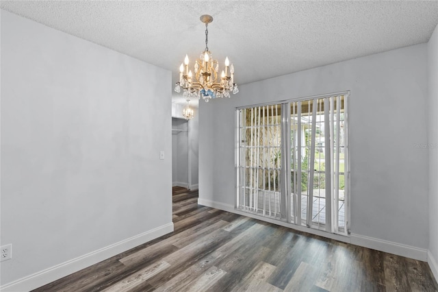 unfurnished dining area with dark hardwood / wood-style flooring, a textured ceiling, and an inviting chandelier