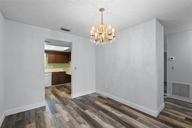 unfurnished dining area with dark wood-type flooring, a textured ceiling, and an inviting chandelier