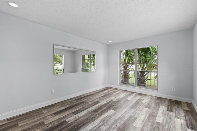 empty room with hardwood / wood-style floors and a textured ceiling