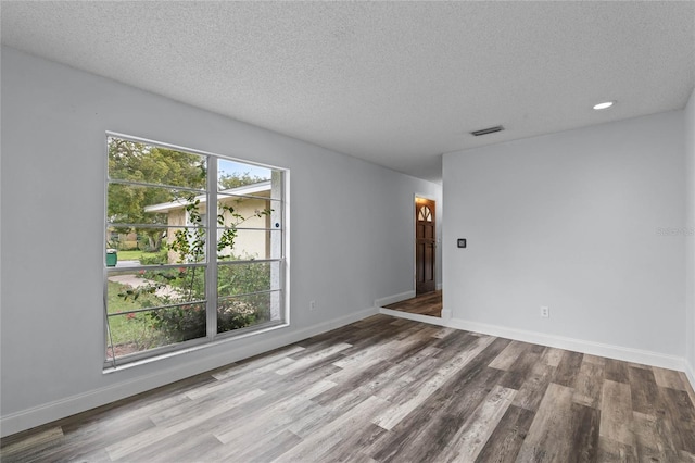 spare room featuring a textured ceiling and hardwood / wood-style flooring