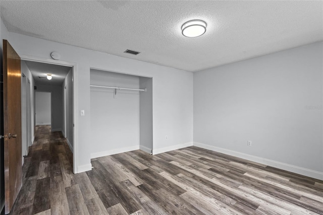 unfurnished bedroom with dark hardwood / wood-style flooring, a textured ceiling, and a closet