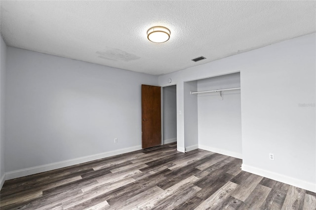 unfurnished bedroom featuring dark wood-type flooring, a textured ceiling, and a closet