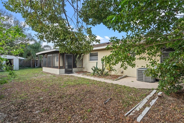 back of property featuring a sunroom, a storage unit, and central AC