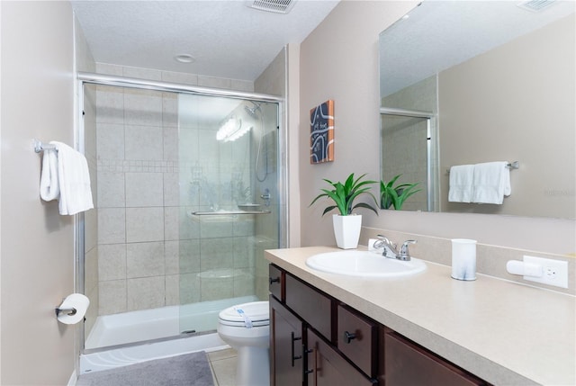 bathroom featuring tile patterned floors, vanity, toilet, and a shower with door