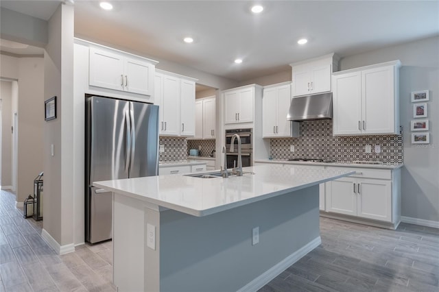 kitchen featuring white cabinets, stainless steel appliances, a kitchen island with sink, and sink