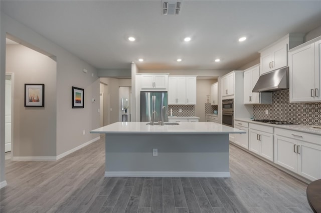 kitchen featuring stainless steel appliances, sink, a center island with sink, light hardwood / wood-style flooring, and white cabinetry