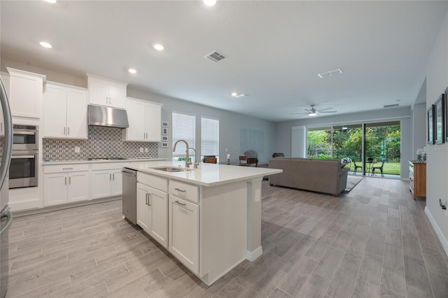 kitchen featuring an island with sink, white cabinetry, ceiling fan, and sink