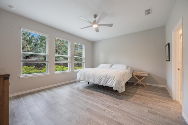 bedroom featuring ceiling fan, light hardwood / wood-style floors, and multiple windows