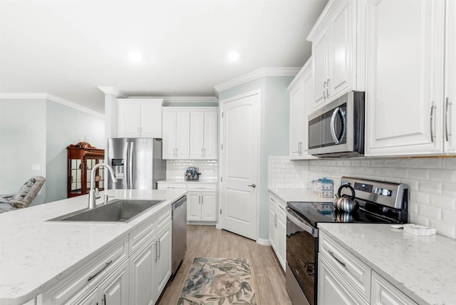 kitchen featuring white cabinetry, sink, backsplash, light hardwood / wood-style floors, and appliances with stainless steel finishes