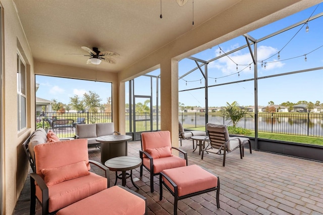 sunroom featuring ceiling fan and a water view