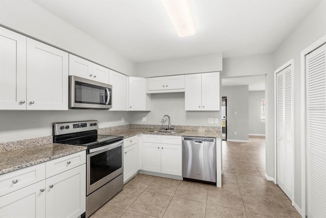 kitchen featuring appliances with stainless steel finishes, light stone counters, white cabinetry, and sink