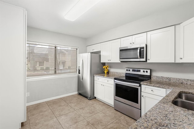 kitchen with light stone countertops, sink, light tile patterned flooring, white cabinets, and appliances with stainless steel finishes