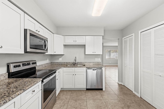 kitchen with white cabinets, sink, light tile patterned floors, appliances with stainless steel finishes, and light stone counters