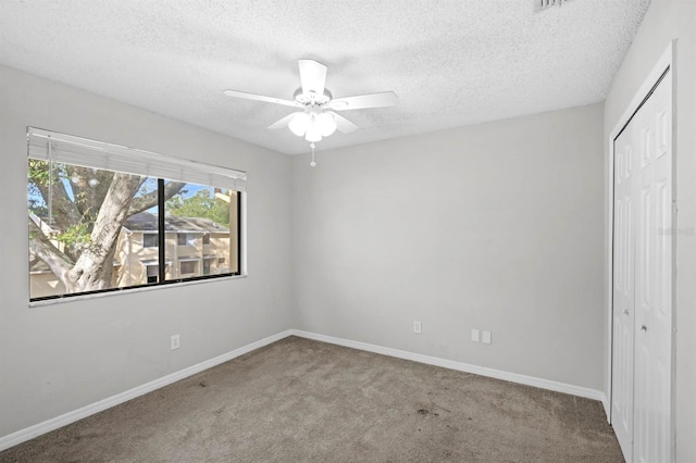 unfurnished bedroom featuring light carpet, a textured ceiling, a closet, and ceiling fan