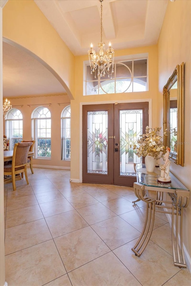 entryway featuring french doors, a towering ceiling, light tile patterned flooring, and a notable chandelier