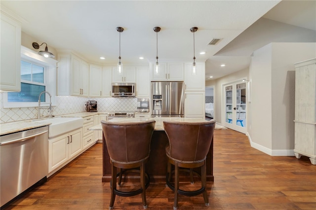 kitchen featuring a center island, stainless steel appliances, decorative light fixtures, and sink