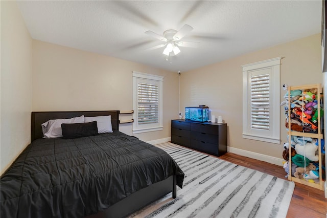 bedroom featuring multiple windows, wood-type flooring, a textured ceiling, and ceiling fan