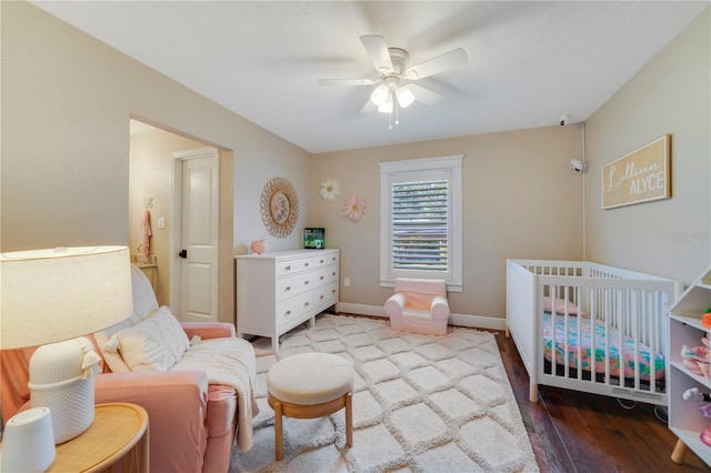 bedroom with ceiling fan, a nursery area, and hardwood / wood-style flooring