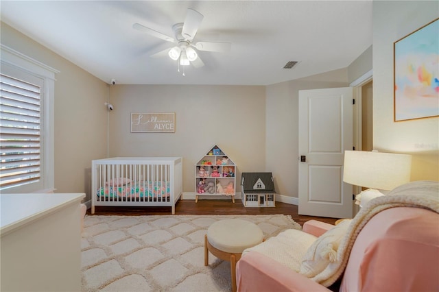 bedroom featuring light hardwood / wood-style flooring, a nursery area, and ceiling fan