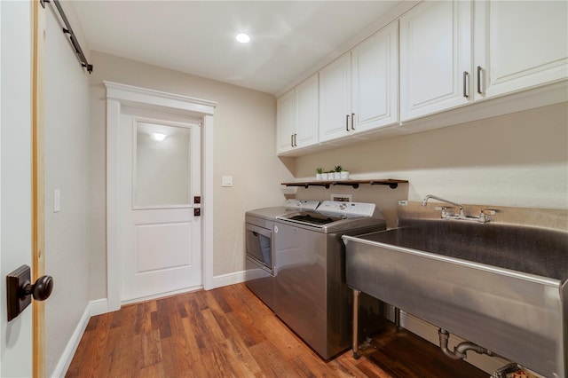 laundry room with sink, cabinets, separate washer and dryer, a barn door, and dark hardwood / wood-style floors