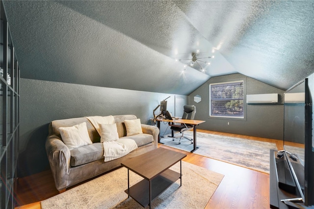 office area with ceiling fan, a wall unit AC, a textured ceiling, vaulted ceiling, and hardwood / wood-style flooring