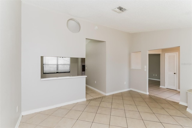 tiled empty room with a textured ceiling