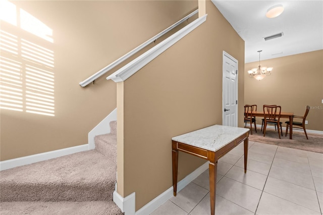 staircase with tile patterned flooring and a notable chandelier