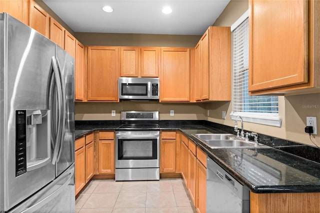 kitchen with dark stone countertops, sink, light tile patterned floors, and appliances with stainless steel finishes