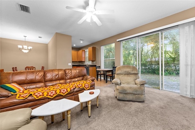 carpeted living room featuring ceiling fan with notable chandelier