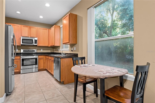 kitchen featuring appliances with stainless steel finishes, light tile patterned floors, a healthy amount of sunlight, and sink