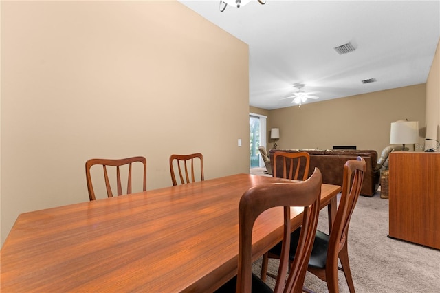 dining area with ceiling fan and light colored carpet